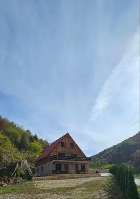a large barn with a red roof on a field at Apartmani Prica in Crni Vrh