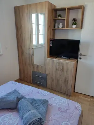 a bedroom with a tv and a bed with blue pillows at APARTMAN TAMARA LUX in Vrnjačka Banja