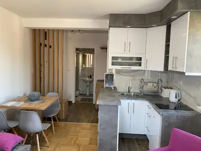 a kitchen with white cabinets and a table and a dining room at APARTMAN TAMARA LUX in Vrnjačka Banja
