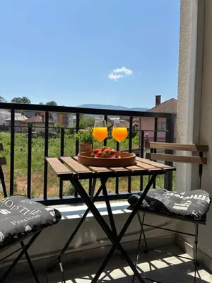 a table with two wine glasses on a balcony at Sweet Dreams & Free parking in Vrnjačka Banja
