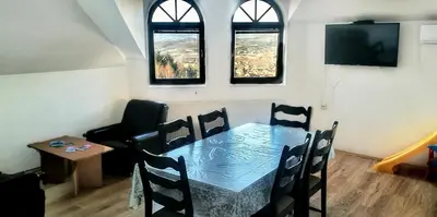 a table and chairs in a room with windows at Apartman Borići in Soko Banja