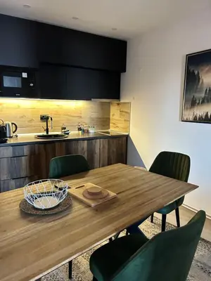 a kitchen with a wooden table and green chairs at Milmari Apartments & SPA - N Lux 108 in Kopaonik