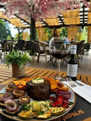 a plate of food on a table with a glass of wine at Hotel Petrus in Paraćin