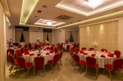 a banquet hall with white tables and red chairs at Hotel Petrus in Paraćin