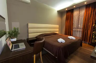 a bedroom with a bed and a desk with a laptop at Hotel Petrus in Paraćin