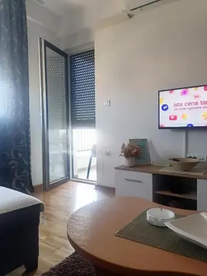 a living room with a table and a flat screen tv at Apartman BojAna Vrnjačka Banja in Vrnjačka Banja