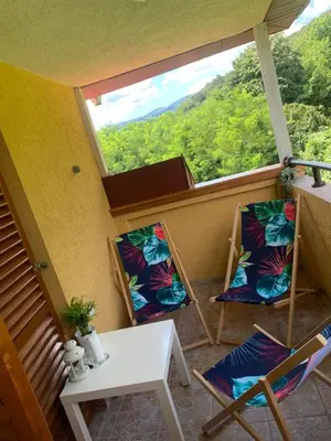 a balcony with two chairs and a table and a window at Vrnjački apartman in Vrnjačka Banja