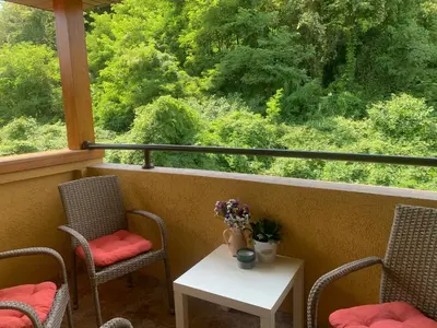 a porch with chairs and a table with flowers on it at Vrnjački apartman in Vrnjačka Banja