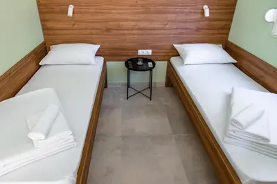 two beds in a small room with a table at Đerdan Garden apartments in Kraljevo