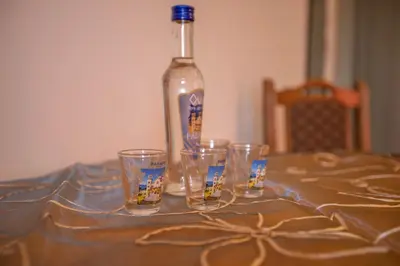 a bottle of alcohol sitting on a table with four glasses at Apartmani Lazić in Ribarska Banja