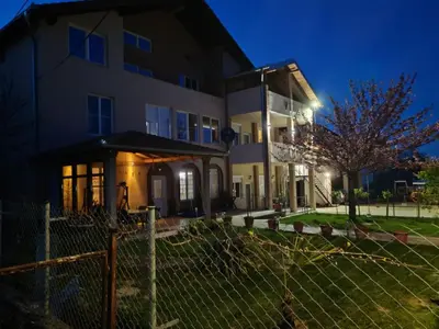 a house with a fence in front of it at night at Apartmani Lazić in Ribarska Banja