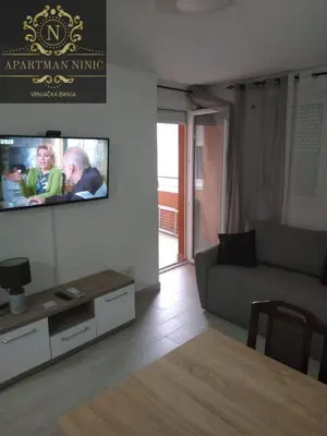 a living room with a couch and a tv on a wall at Apartman Ninic in Vrnjačka Banja