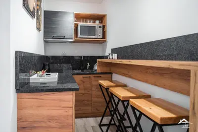 a kitchen with wooden counters and a microwave and stools at J&S Apartments in Niš