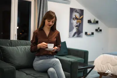 a woman sitting on a couch looking at her tablet at J&S Apartments in Niš