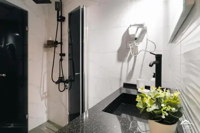 a bathroom with a shower with a sink and flowers at J&S Apartments in Niš