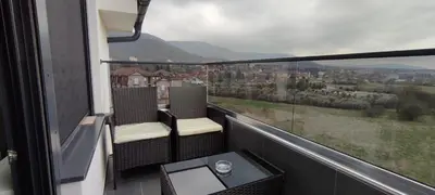 a balcony with two chairs and a table and a view at Jela Apartman in Soko Banja