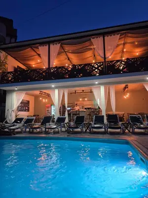a large swimming pool with chairs and a house at Garni Hotel Panorama Lux in Niš