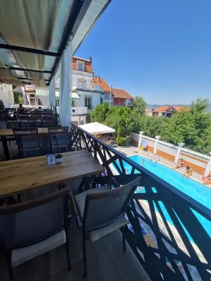 a balcony with a table and chairs and a swimming pool at Garni Hotel Panorama Lux in Niš