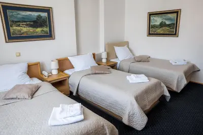 a room with three beds with towels on them at Garni Hotel Panorama Lux in Niš