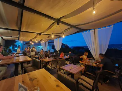 a group of people sitting at tables in a restaurant at Garni Hotel Panorama Lux in Niš