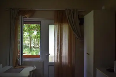 a room with a window and a door with curtains at Apartmani Filip in Vrnjci