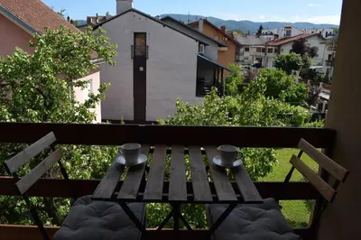 a wooden bench sitting on a balcony with two cups at Apartmani Filip in Vrnjci