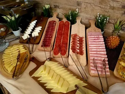 a table topped with different types of meats and cheese at Hotel Marica in Niš