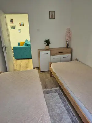 a bedroom with two beds and a blue couch at Apartmani Bubamara Leskovac in Leskovac