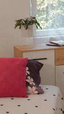 a red pillow sitting on a bed next to a window at Apartmani Bubamara Leskovac in Leskovac
