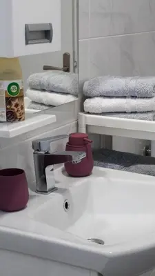 a bathroom sink with a red faucet and towels at Apartmani Bubamara Leskovac in Leskovac