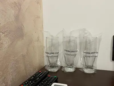 three empty glasses sitting on a table next to a remote control at Apartmani Bosfor in Niška Banja