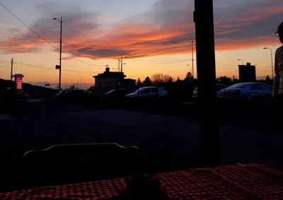 a sunset with cars parked in a parking lot at Apartmani Bosfor in Niška Banja