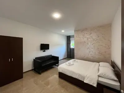a bedroom with a bed and a chair and a television at Apartmani Bosfor in Niška Banja