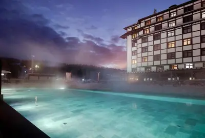 a swimming pool in front of a building at night at Hotel Grand Kopaonik in Kopaonik