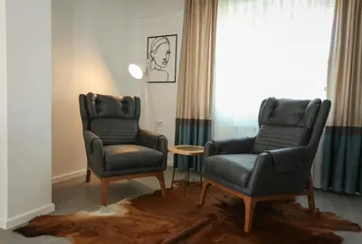 two chairs and a table in a room with a window at Apartmani Freedom place in Jagodina