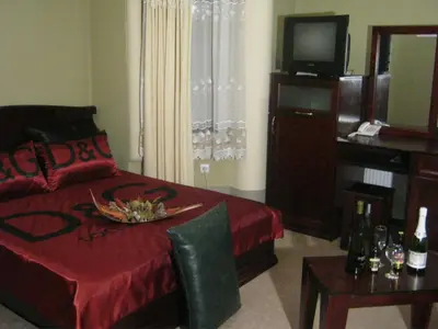 a bedroom with a bed and a television and a table at HOTEL VILA MITIC LUXX SPA centar in Leskovac