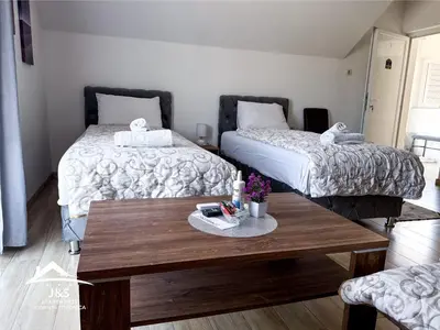 a room with two beds and a wooden table at J&S Apartments - Gornja Toponica in Gornja Toponica