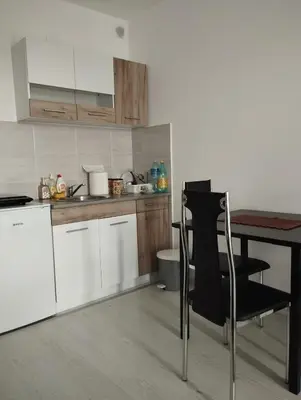 a kitchen with white cabinets and a table with a black chair at Maki i Jeka in Soko Banja