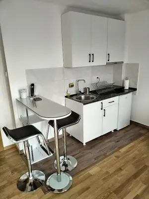 a kitchen with white cabinets and a sink and a table at Apartman Ida in Soko Banja