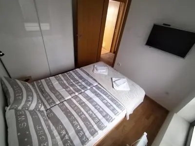 a small bedroom with a bed and a flat screen tv at Apartman Ida in Soko Banja