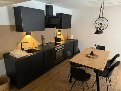 a kitchen with black cabinets and a wooden table at Hestia Suite in Zaječar