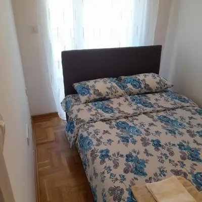 a bedroom with a bed with a blue and white comforter at Apartman Ignjatović in Vrnjačka Banja