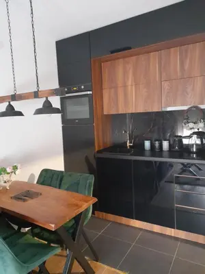 a kitchen with a wooden table and a stove at Vrnjačka Promenada - Pešačka zona - Baby friendly in Vrnjačka Banja