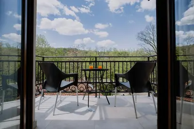 a balcony with a table and chairs looking out the window at Terra Apartments in Vrnjačka Banja