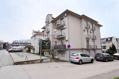 a building with cars parked in front of it at Apartman Dačić in Vrnjačka Banja