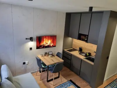 a kitchen with a table and a fire in the wall at ANIMA Bela reka C121, Brzeće in Brzeće