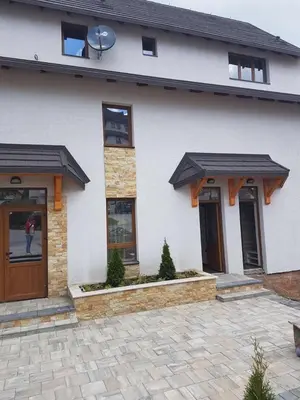 a white house with two brown doors and a patio at Apartman na Kopaoniku in Kopaonik
