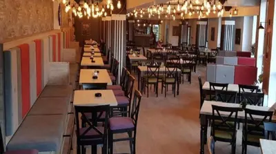 a dining room with tables and chairs and chandeliers at Apartman na Kopaoniku in Kopaonik