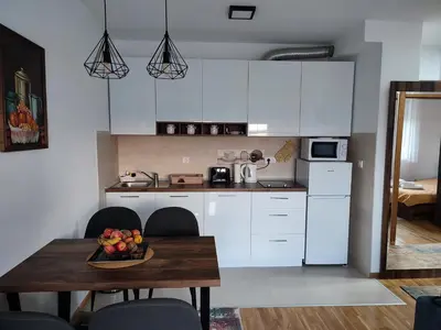 a kitchen with white cabinets and a table with a bowl of fruit on it at Apartman Desanka in Vrnjačka Banja