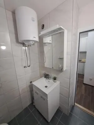 a white bathroom with a sink and a mirror at Daka in Vrnjačka Banja